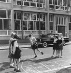 848116 Afbeelding van een groep meisjes die hinkelen op straat, vermoedelijk in Amsterdam-West.